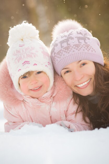 Glückliche Familie, die im Winterpark auf Schnee liegt