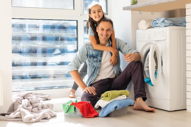 Glückliche Familie, die Kleidung in die Waschmaschine zu Hause lädt