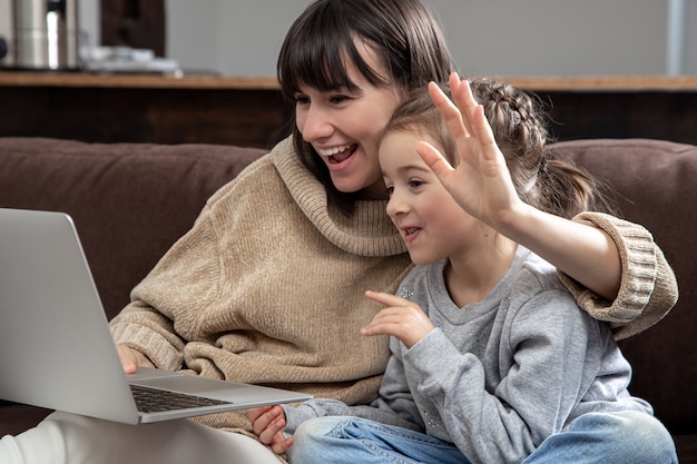 Glückliche Familie, die Laptop-Bildschirm betrachtet, machen Fernvideoanruf. Lächelnde Mutter und kleines Mädchen sprechen mit Webkamera im Internet-Chat.