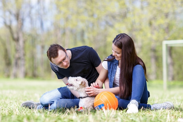 Glückliche Familie, die mit Hund im Park spielt