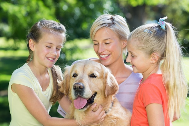 Glückliche Familie, die mit ihrem Hund spielt