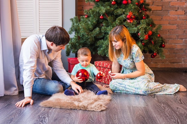 Glückliche Familie, die mit Weihnachtskugeln zu Hause spielt