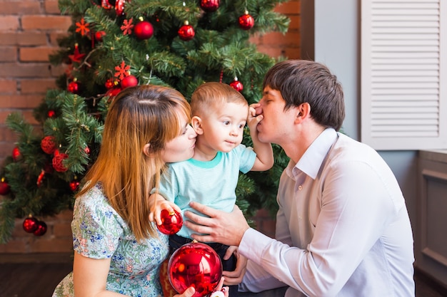 Glückliche Familie, die mit Weihnachtskugeln zu Hause spielt