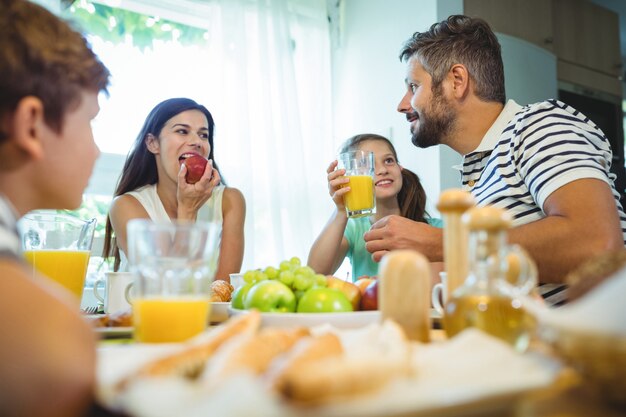 Glückliche Familie, die miteinander spricht, während sie zusammen frühstücken