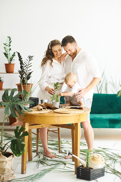 Glückliche Familie, die nach Hause arbeitet. Pflanzen mit ihrem Kind umpflanzen