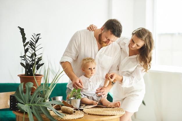 Glückliche Familie, die nach Hause arbeitet. Pflanzen mit ihrem Kind umpflanzen