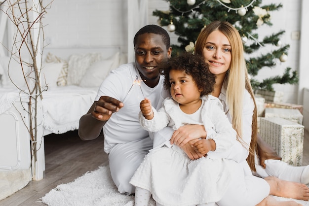 Glückliche Familie, die nahe dem Weihnachtsbaum sitzt