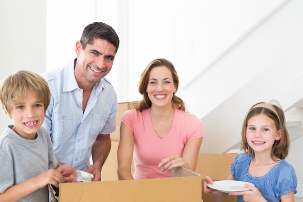 Glückliche Familie, die Pappschachtel im Haus auspackt