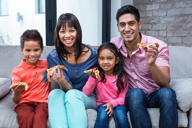 Glückliche Familie, die Pizza auf dem Sofa isst