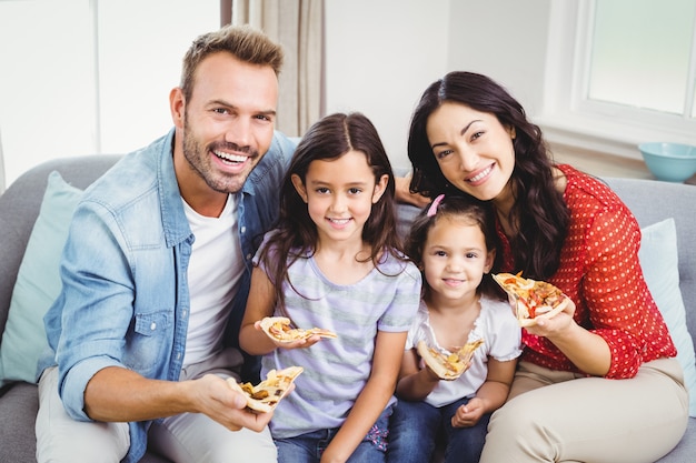 Glückliche Familie, die Pizza beim Sitzen auf Sofa isst