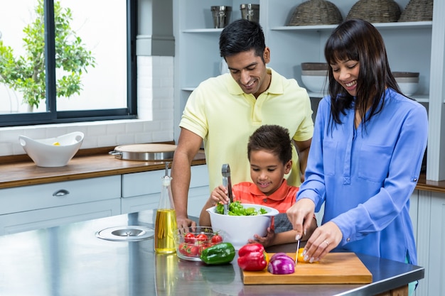 Glückliche Familie, die Salat in der Küche zubereitet