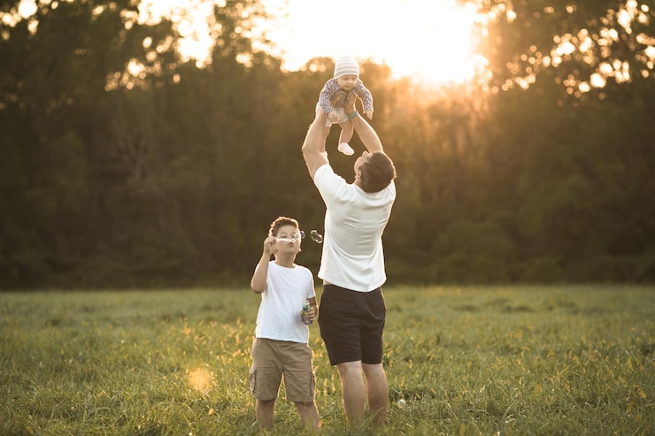 Foto glückliche familie, die sich auf einem sommerspaziergang umarmt und umarmt. vater und seine beiden söhne gehen im park spazieren und genießen die wunderschöne natur. niedliches familienporträt