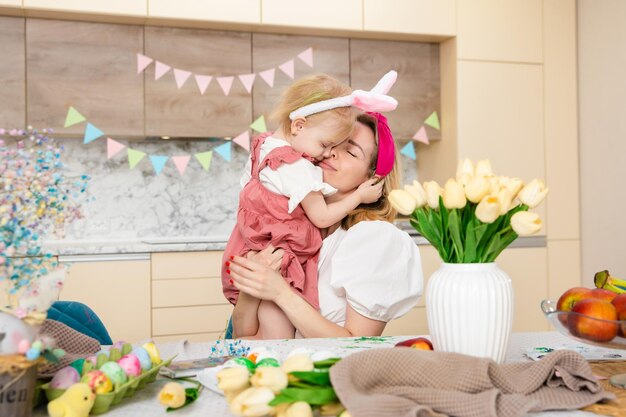 Glückliche Familie, die sich auf Ostern vorbereitet Süßes Mädchen, das Mutter umarmt Heimaktivität Konzept der Einheit und Liebe Mutter und Tochter