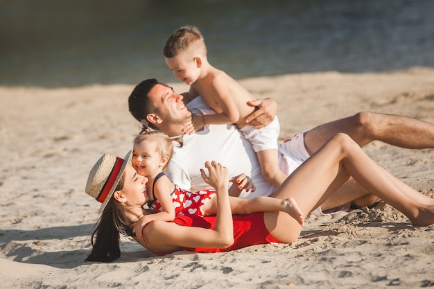 Glückliche Familie, die Spaß am Strand hat. Mama, Papa, Sohn und kleine Tochter am Meer. Fröhliche Familie