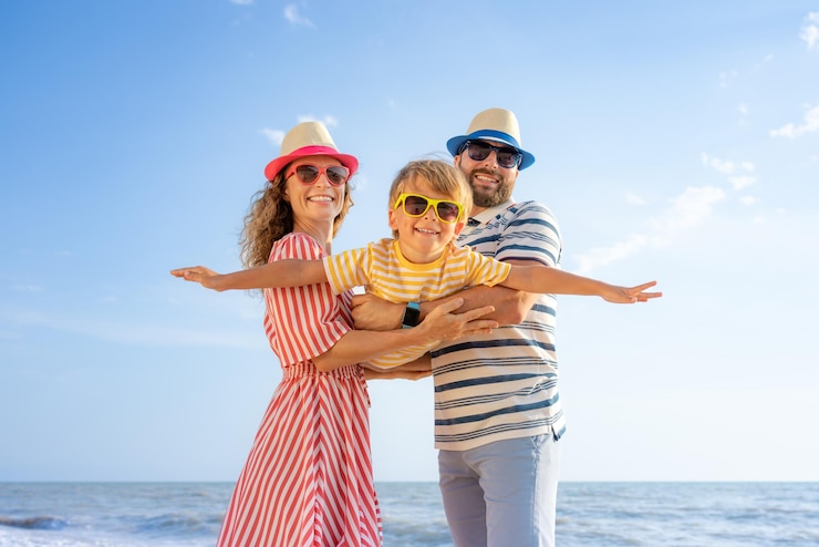 Foto glückliche familie, die spaß am strand hat mutter und vater halten sohn vor blauem meer und himmelshintergrund sommerurlaubskonzept