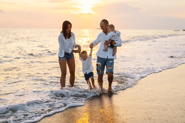 Glückliche Familie, die Spaß beim Strandspielen im Sommerurlaub am Strand hat Glückliche Familie und Urlaub-Konzept Meereslandschaft bei Sonnenuntergang mit schönem Himmel Familie am Strand