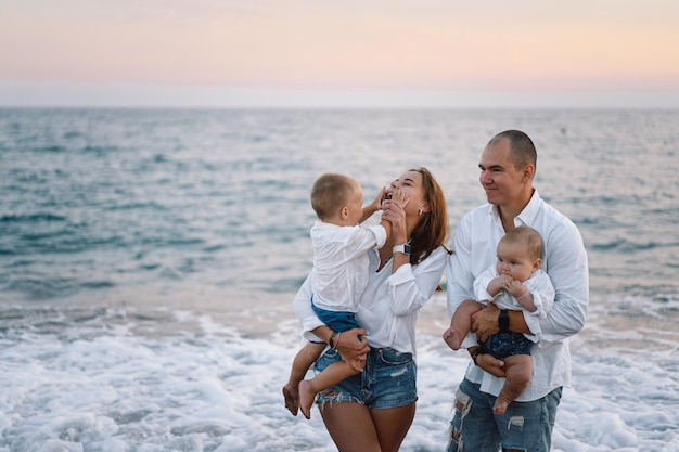 Glückliche Familie, die Spaß beim Strandspielen im Sommerurlaub am Strand hat Glückliche Familie und Urlaub-Konzept Meereslandschaft bei Sonnenuntergang mit schönem Himmel Familie am Strand