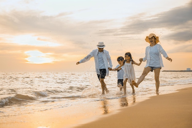 Glückliche Familie, die Spaß daran hat, bei Sonnenuntergang am Sandstrand zu laufen