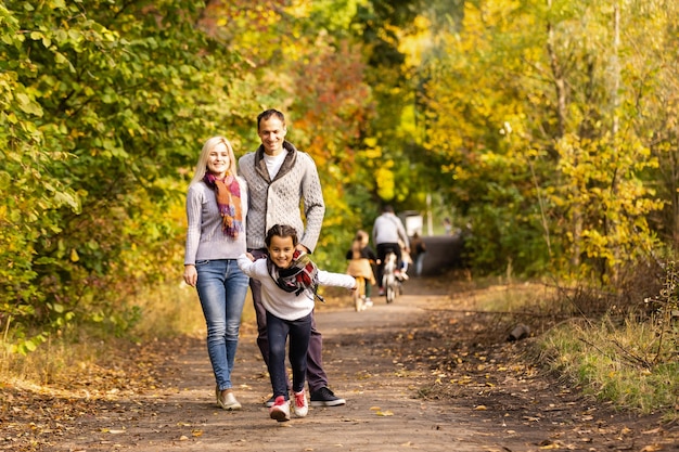 Glückliche Familie, die Spaß im Freien im Herbstpark gegen unscharfen Blätterhintergrund hat