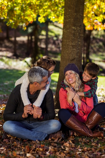 Glückliche Familie, die unter Baum am Park sitzt