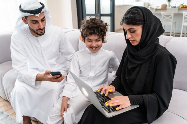 Glückliche Familie, die Zeit zusammen verbringt. Arabische Eltern und ihr Sohn spielen und machen verschiedene Aktivitäten zu Hause