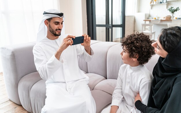 Glückliche Familie, die Zeit zusammen verbringt. Arabische Eltern und ihr Sohn spielen und machen verschiedene Aktivitäten zu Hause