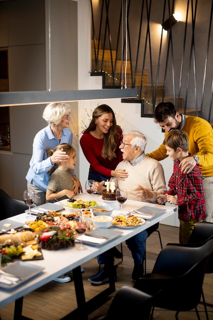 Glückliche Familie, die zu Hause Großvatergeburtstag mit Kuchen und Kerzen feiert
