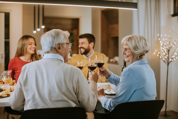 Glückliche Familie, die zu Hause mit Rotwein zu Abend isst