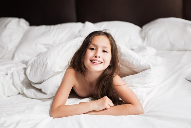 Glückliche Familie, die zu Hause unter der Decke im Bett liegt