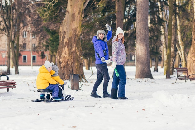 Glückliche Familie, die zusammen im Winterpark geht, zwei erwachsene Mann und Frau und zwei Kinder