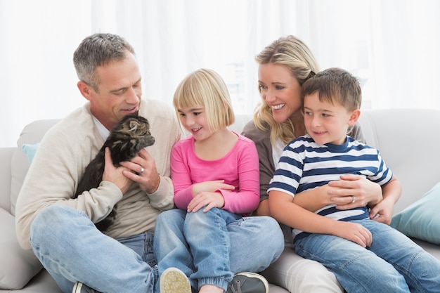Glückliche Familie, die zusammen mit Haustierkätzchen sitzt
