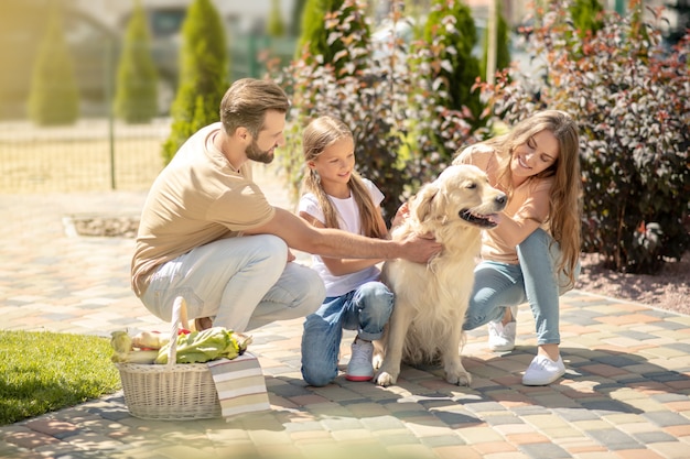 Glückliche Familie, die zusammen mit ihrem Hund spazieren geht