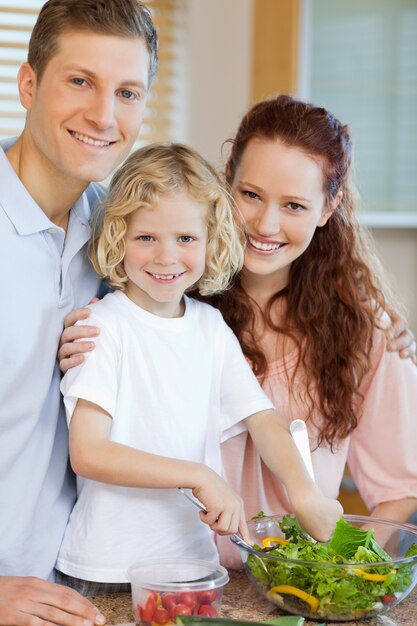 Glückliche Familie, die zusammen Salat zubereitet