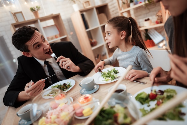 Glückliche Familie, die zusammen Teller am Tisch isst.