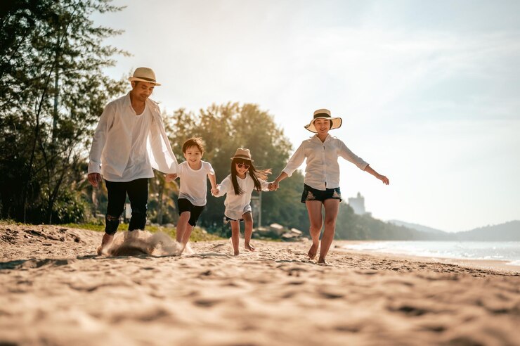 Glückliche Familie Eltern halten ihre Kinder an den Händen und gehen im Urlaub am Strand spazierenFamilienreisen Strand entspannen Lifestyle-Urlaubskonzept