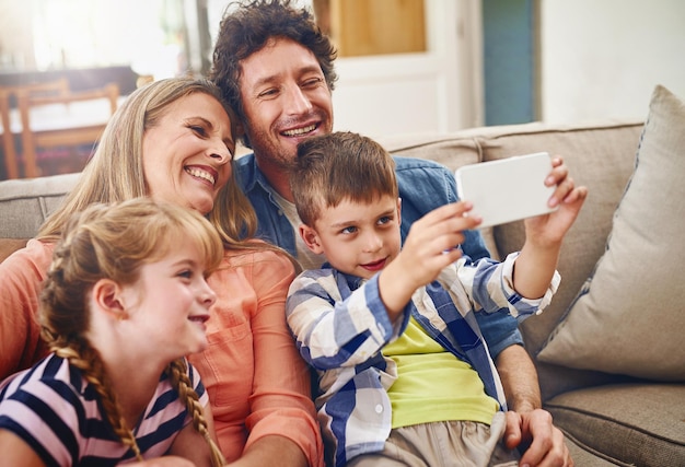 Glückliche Familie entspannen und Sofa mit Selfie für Bildfotografie oder Erinnerung zusammen zu Hause Mutter Vater und kleine Kinder mit Lächeln für Bindung Urlaub oder Wochenende Moment auf der Couch zu Hause