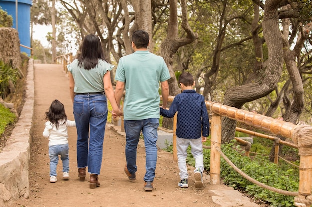 Glückliche Familie hält Händchen und spaziert am Nachmittag durch den Park