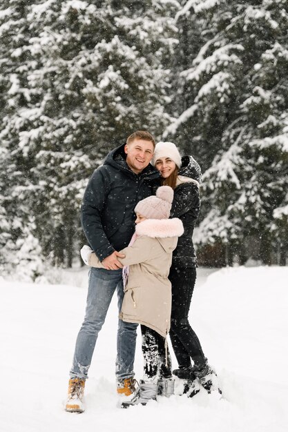 Glückliche Familie hat Spaß im Winterwald. Mutter, Vater und Tochter spielen mit Schnee. Familienkonzept