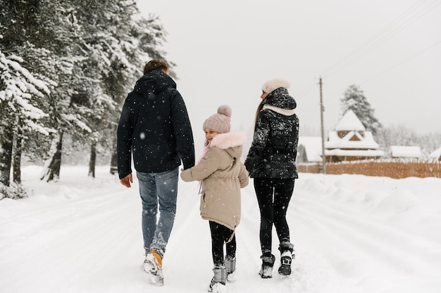 Glückliche Familie hat Spaß im Winterwald. Mutter, Vater und Tochter spielen mit Schnee. Genießen Sie die gemeinsame Zeit. Familienkonzept