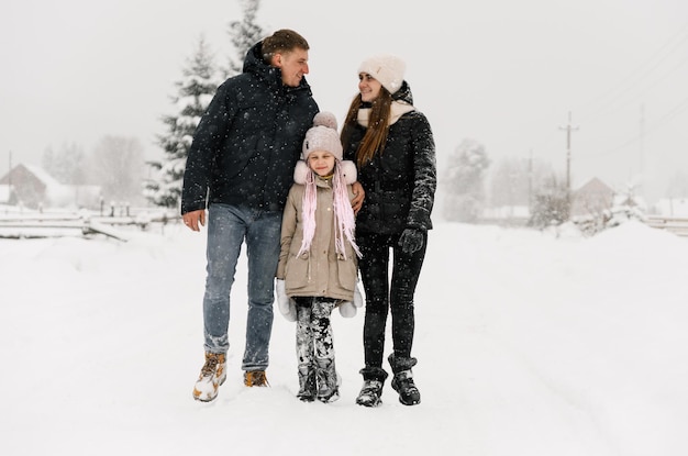 Glückliche Familie hat Spaß im Winterwald. Mutter, Vater und Tochter spielen mit Schnee. Genießen Sie die gemeinsame Zeit. Familienkonzept