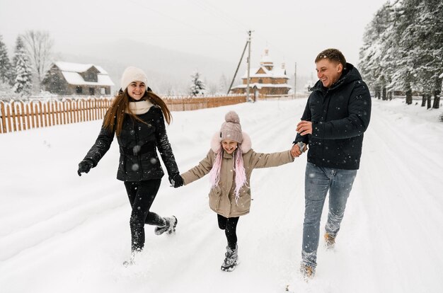 Glückliche Familie hat Spaß im Winterwald. Mutter, Vater und Tochter spielen mit Schnee. Genießen Sie die gemeinsame Zeit. Familienkonzept