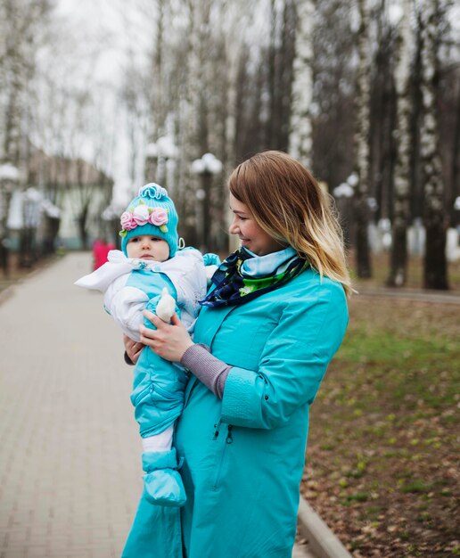 Glückliche Familie im Freien junge Mutter geht mit kleinem Baby im FrühlingsstadtspielplatzxDxA spazieren