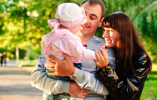 Glückliche Familie im Freien - Mutter, Vater und Tochter lächeln