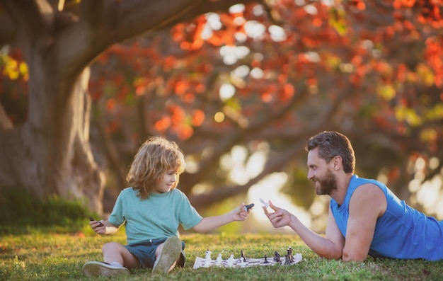 Glückliche Familie im Freien. Vater und Sohn spielen Schach im Herbstgarten.