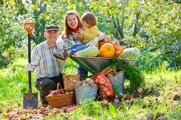 Glückliche Familie im Garten mit einer Ernte von Gemüse und Obst