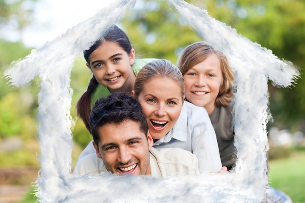 Glückliche Familie im Park gegen Hausumriss in Wolken