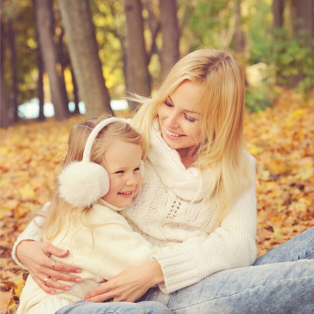 Glückliche Familie im Park, lächelnde Mutter und kleine Tochter machen eine Pause im Herbstpark