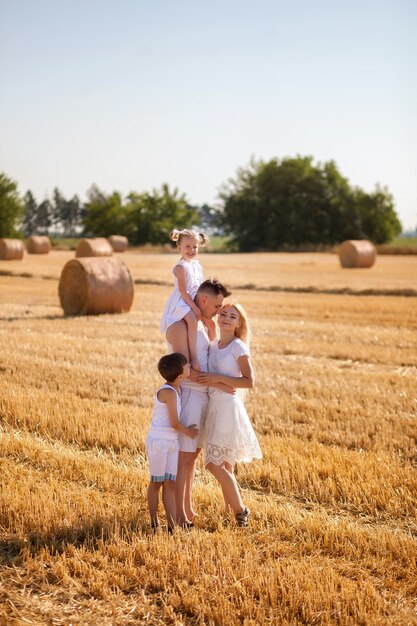 Glückliche Familie im Sommer auf einem Feld mit Heuhaufen