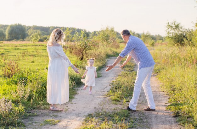 Glückliche Familie im Sommerpark bei Sonnenuntergang