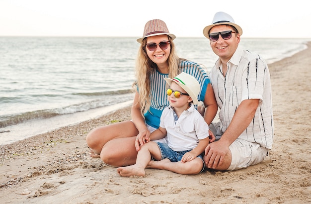 Glückliche familie im urlaub. am strand sitzen mama, papa und ein kleiner sohn. reisende familie. küsse, lächelt.